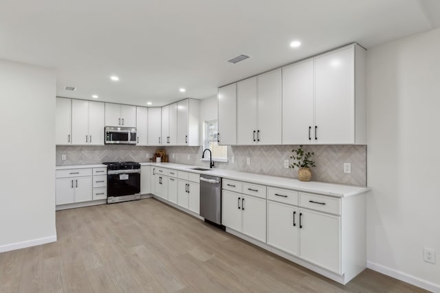 kitchen featuring visible vents, a sink, appliances with stainless steel finishes, light wood finished floors, and light countertops