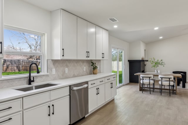 kitchen featuring light wood-style flooring, a sink, tasteful backsplash, recessed lighting, and dishwasher