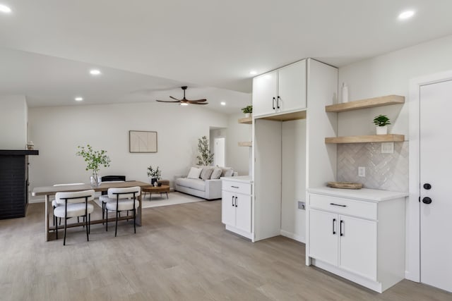 kitchen featuring light wood finished floors, ceiling fan, decorative backsplash, light countertops, and white cabinets