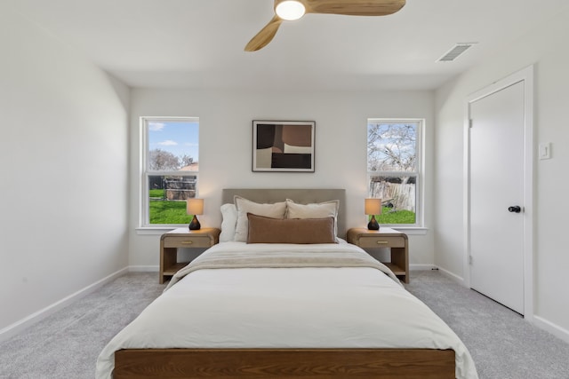 bedroom with visible vents, light colored carpet, and multiple windows