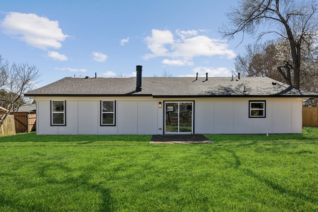 back of house with a shingled roof, a yard, and fence