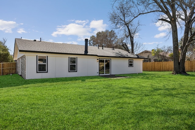 back of property with a lawn and fence