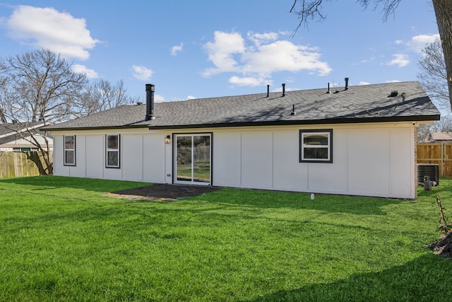 back of house featuring cooling unit, fence, a lawn, and a shingled roof