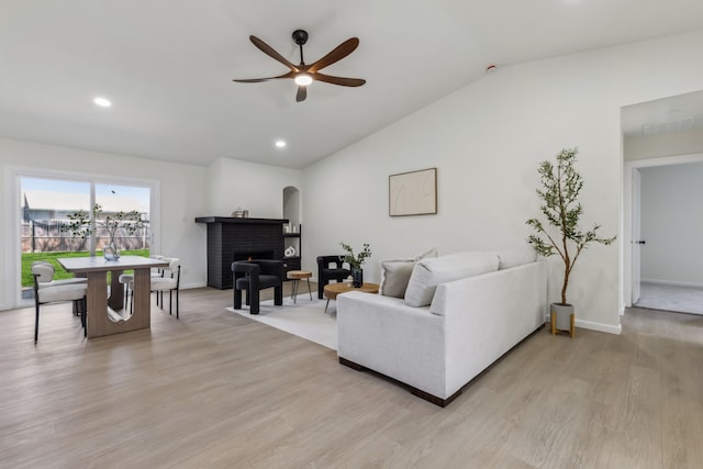 living area featuring recessed lighting, ceiling fan, vaulted ceiling, a brick fireplace, and light wood-type flooring