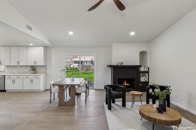 dining space featuring visible vents, lofted ceiling, a ceiling fan, light wood-style floors, and baseboards