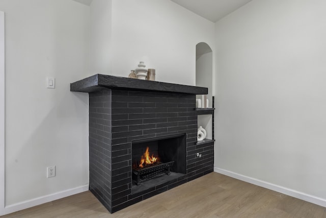 details with baseboards, a brick fireplace, and wood finished floors