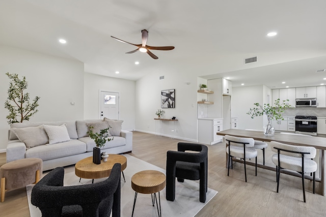 living area with visible vents, a ceiling fan, light wood-style floors, and lofted ceiling