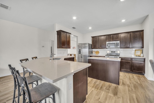 kitchen with visible vents, a sink, dark brown cabinets, appliances with stainless steel finishes, and a center island