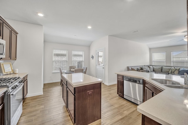 kitchen featuring a wealth of natural light, a sink, open floor plan, a center island, and appliances with stainless steel finishes