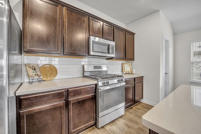 kitchen with tasteful backsplash, dark brown cabinetry, light wood-type flooring, light countertops, and appliances with stainless steel finishes