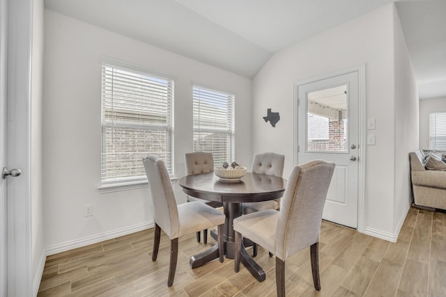 dining area featuring vaulted ceiling, baseboards, and light wood-type flooring