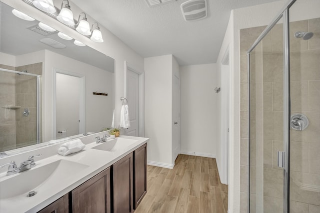 full bathroom with visible vents, a shower stall, wood finished floors, and a sink