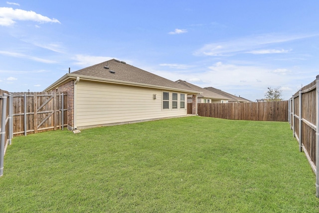 exterior space with a yard, brick siding, roof with shingles, and a fenced backyard