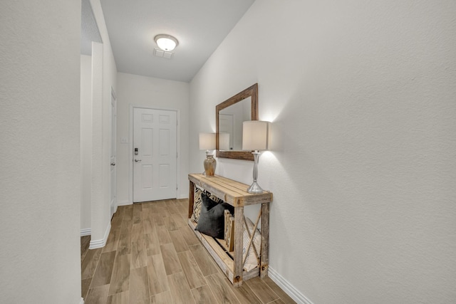 hall featuring light wood finished floors, visible vents, and baseboards