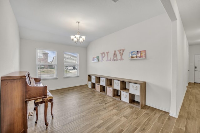 sitting room featuring light wood finished floors, baseboards, a chandelier, vaulted ceiling, and arched walkways