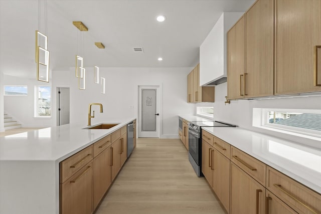 kitchen featuring visible vents, light wood-style flooring, a sink, stainless steel appliances, and light countertops