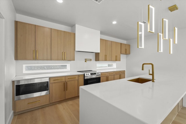 kitchen with light wood-style flooring, recessed lighting, a sink, light countertops, and appliances with stainless steel finishes