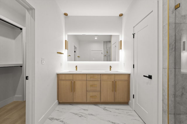 bathroom featuring double vanity, a stall shower, marble finish floor, and a sink