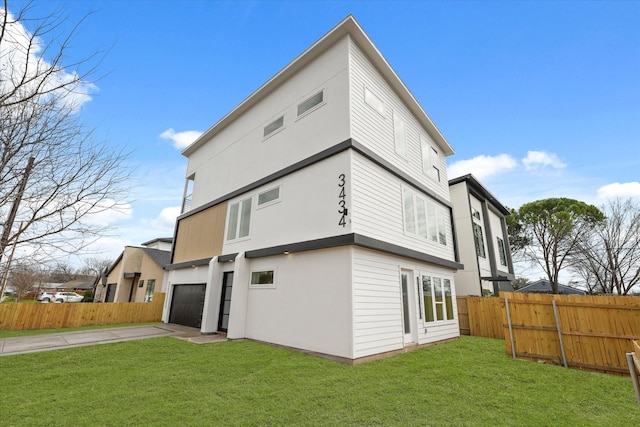 rear view of property featuring fence, concrete driveway, stucco siding, a lawn, and an attached garage