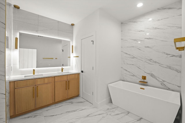 bathroom with marble finish floor, a sink, recessed lighting, double vanity, and a freestanding bath