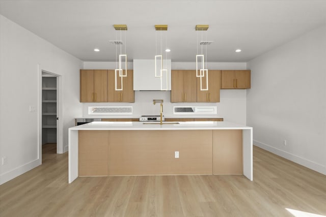 kitchen with visible vents, light wood-style flooring, a sink, light countertops, and exhaust hood