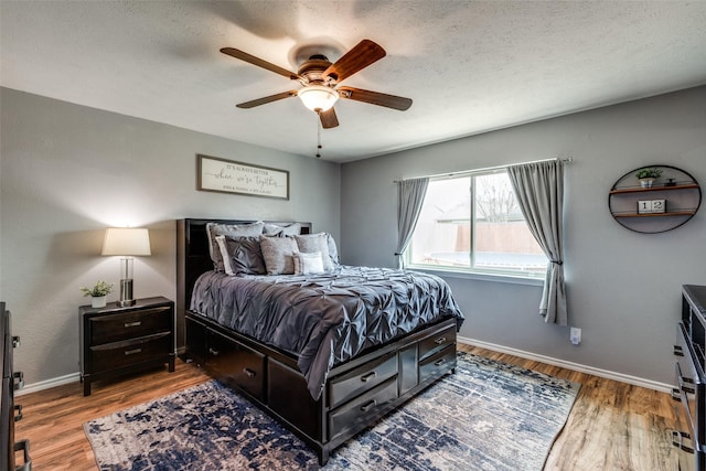 bedroom featuring a textured ceiling, a ceiling fan, baseboards, and wood finished floors