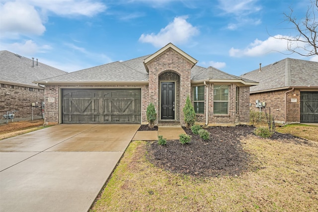 view of front of property with a garage, brick siding, roof with shingles, and concrete driveway