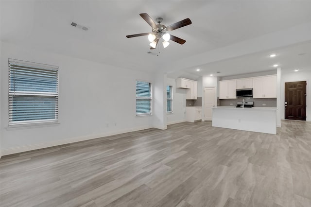 unfurnished living room with a ceiling fan, visible vents, baseboards, light wood-style flooring, and recessed lighting