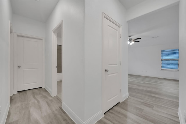 corridor featuring light wood-type flooring and baseboards