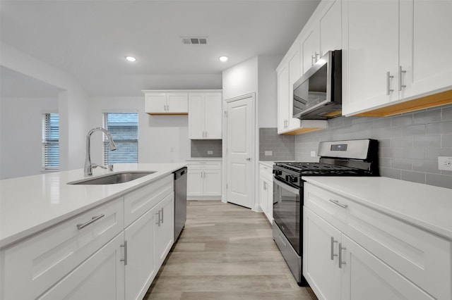 kitchen with visible vents, a sink, appliances with stainless steel finishes, light countertops, and decorative backsplash