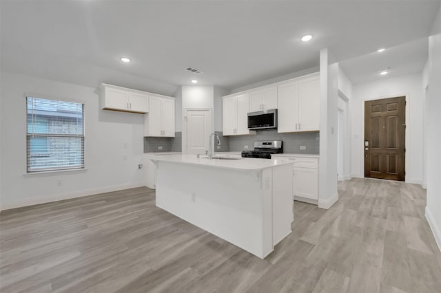 kitchen featuring backsplash, white cabinets, appliances with stainless steel finishes, and a sink