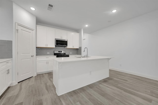 kitchen with backsplash, appliances with stainless steel finishes, light countertops, and a sink