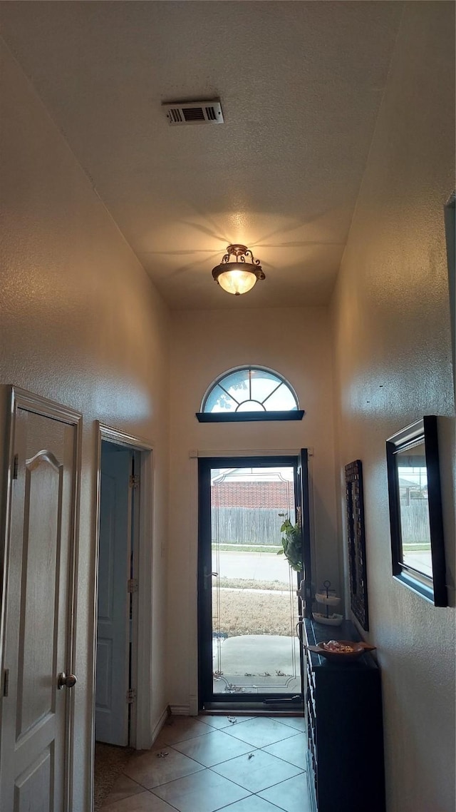 entrance foyer with light tile patterned floors, visible vents, a textured ceiling, and a textured wall