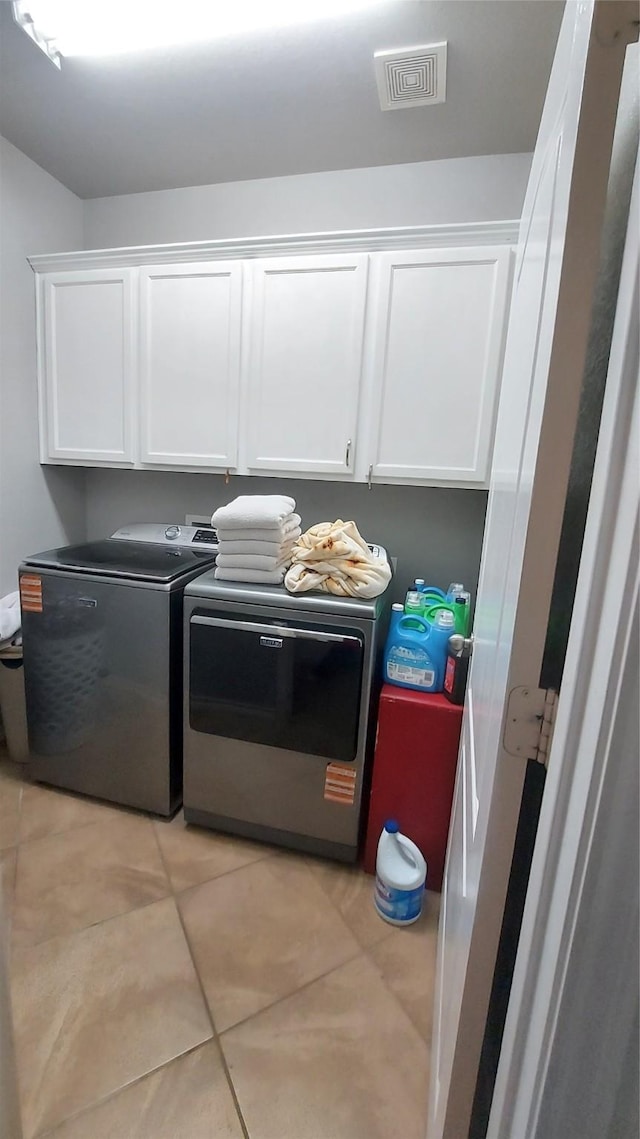 washroom featuring light tile patterned floors, cabinet space, visible vents, and washing machine and clothes dryer