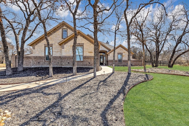 french country home with brick siding and a front yard