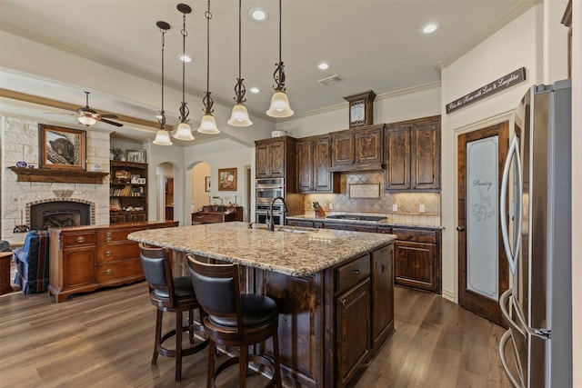 kitchen with ornamental molding, a ceiling fan, a sink, arched walkways, and appliances with stainless steel finishes