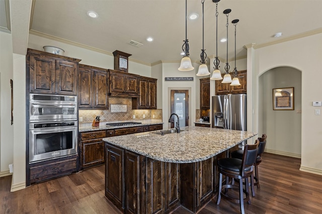117 Birdie Dr, Lipan, TX 76462 - kitchen with stainless steel appliances, ornamental molding, dark wood-style flooring, dark brown cabinetry, and a kitchen island with sink
