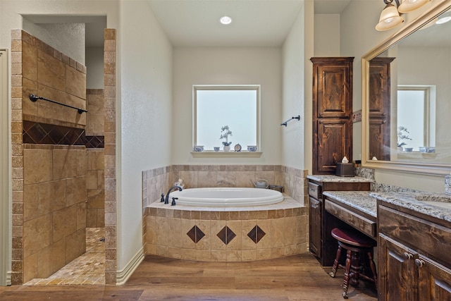 full bathroom with wood finished floors, walk in shower, a bath, and vanity