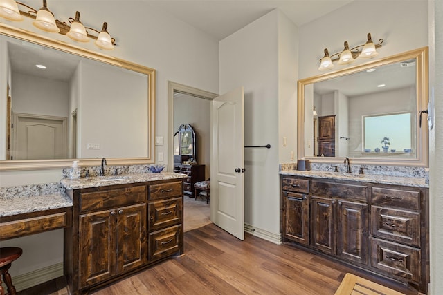 full bath featuring a sink, two vanities, and wood finished floors