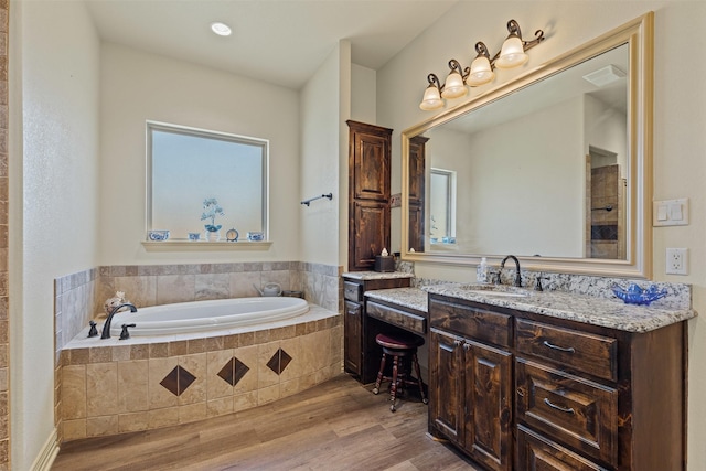 full bathroom featuring vanity, a bath, wood finished floors, and visible vents