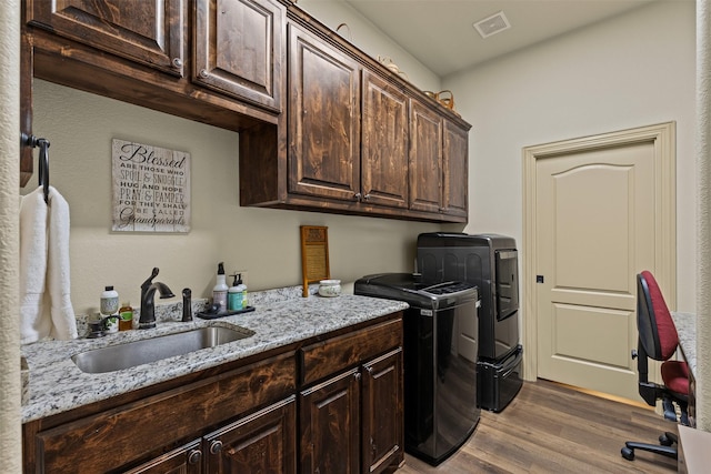 laundry area featuring visible vents, washer and clothes dryer, a sink, wood finished floors, and cabinet space