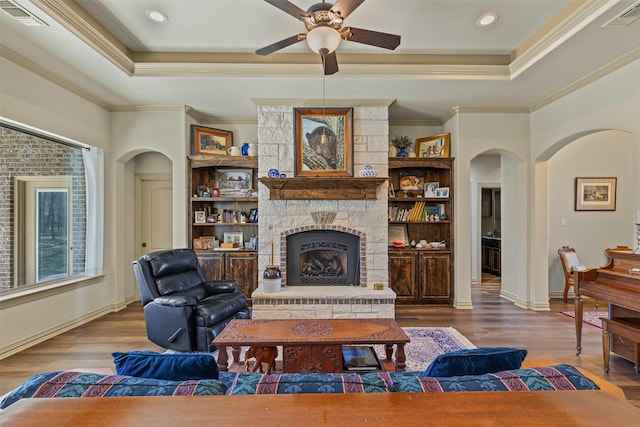 117 Birdie Dr, Lipan, TX 76462 - living room featuring a raised ceiling, arched walkways, ceiling fan, wood finished floors, and ornamental molding