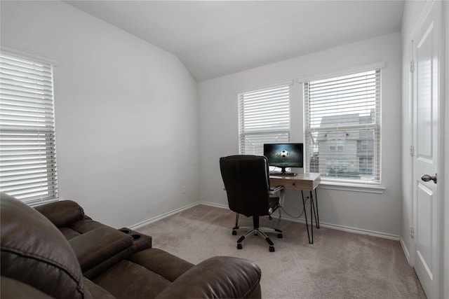 home office featuring lofted ceiling, baseboards, and light carpet