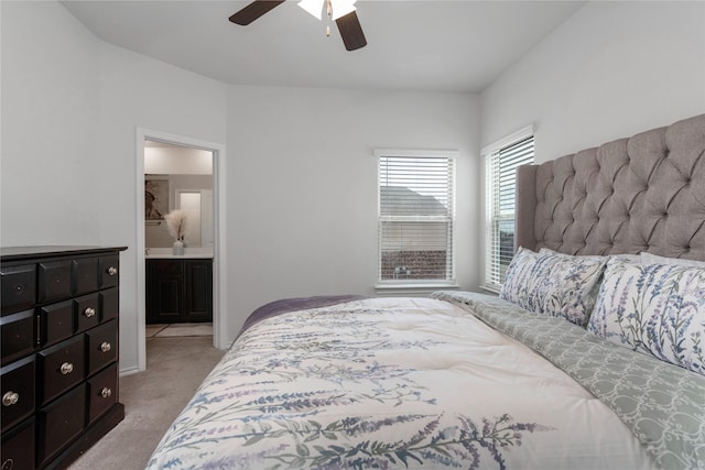 bedroom featuring light carpet, ceiling fan, and ensuite bathroom