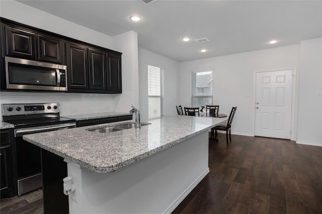 kitchen with visible vents, a sink, dark wood finished floors, stainless steel appliances, and light stone countertops