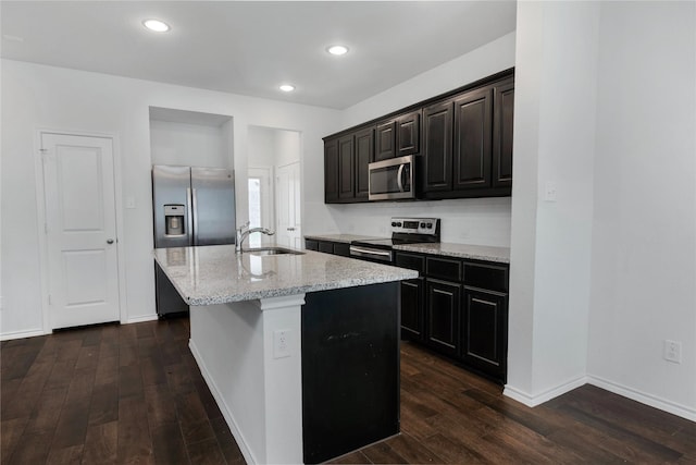 kitchen with dark wood finished floors, a center island with sink, appliances with stainless steel finishes, and a sink