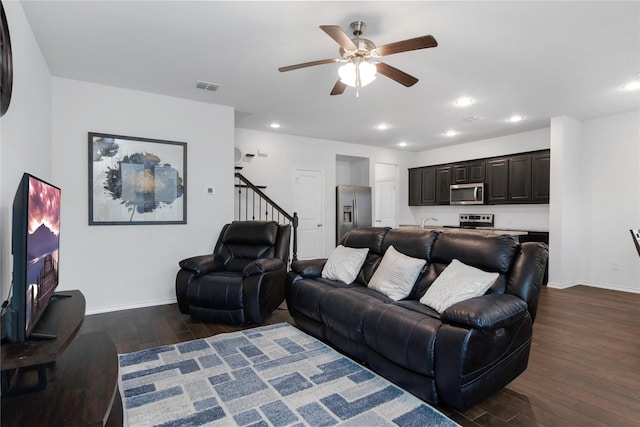 living area featuring dark wood-style floors, baseboards, visible vents, a ceiling fan, and stairs