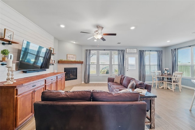 living area featuring light wood-style flooring, recessed lighting, baseboards, ceiling fan, and a tile fireplace