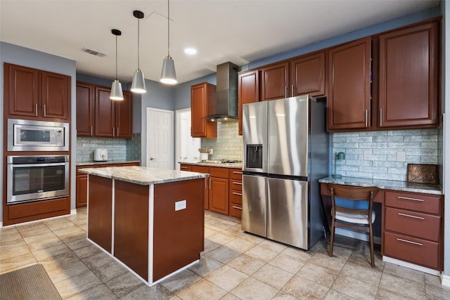 kitchen with visible vents, a kitchen island, wall chimney range hood, decorative light fixtures, and stainless steel appliances