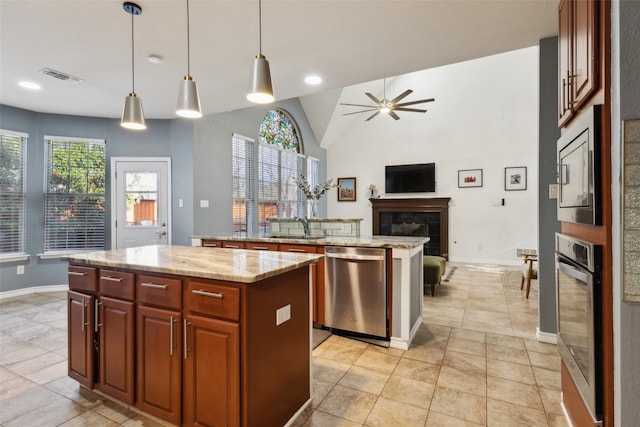 kitchen with visible vents, a ceiling fan, a sink, a kitchen island, and appliances with stainless steel finishes